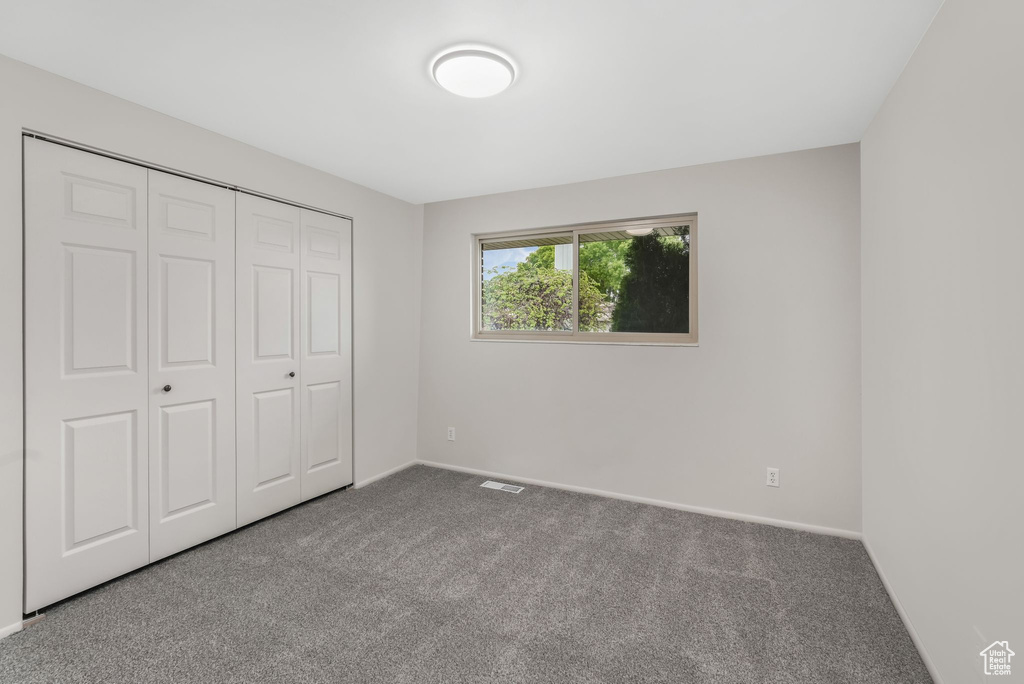 Unfurnished bedroom featuring carpet floors, baseboards, visible vents, and a closet