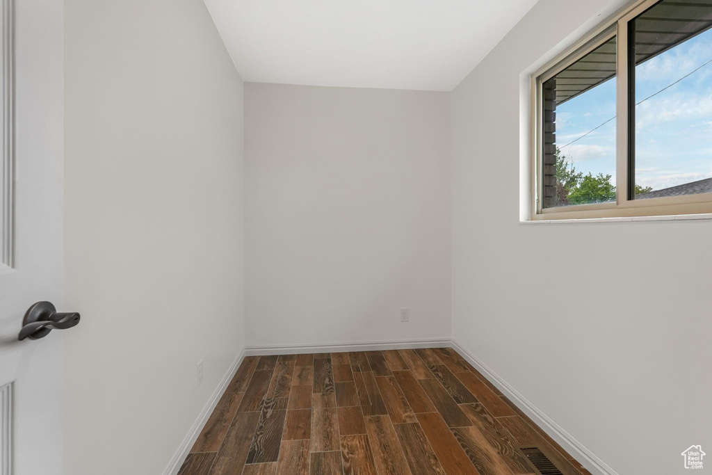 Spare room with baseboards and dark wood-style flooring
