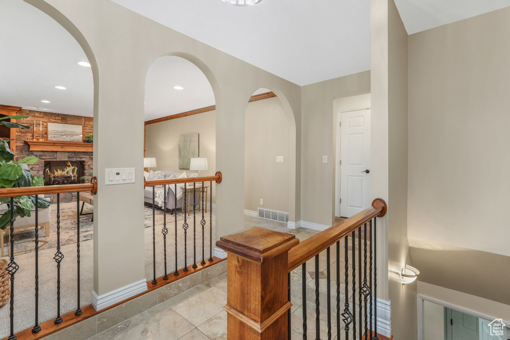 Hallway with visible vents, baseboards, recessed lighting, arched walkways, and an upstairs landing