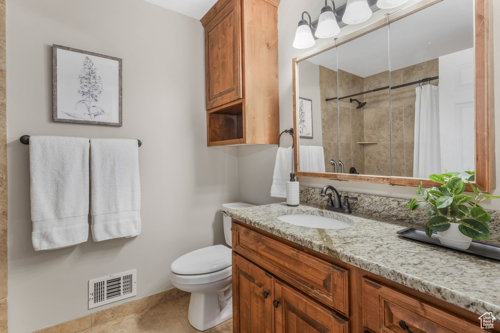 Full bathroom featuring a tile shower, vanity, toilet, tile patterned floors, and visible vents