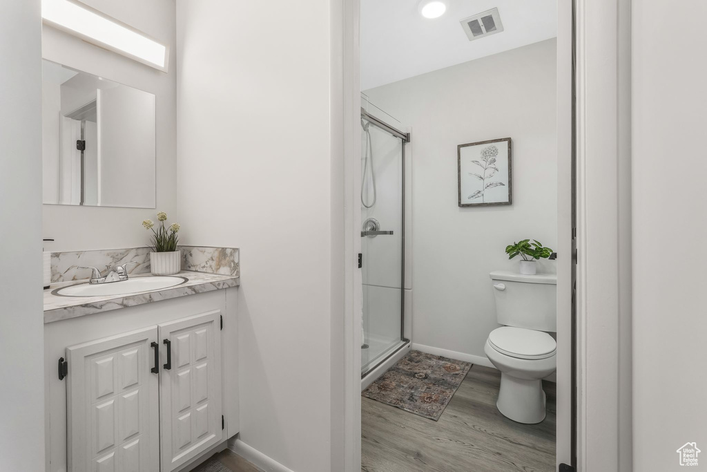 Full bathroom with vanity, wood finished floors, toilet, baseboards, and a stall shower