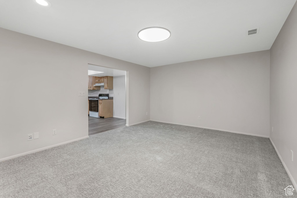 Spare room featuring baseboards, visible vents, and light carpet