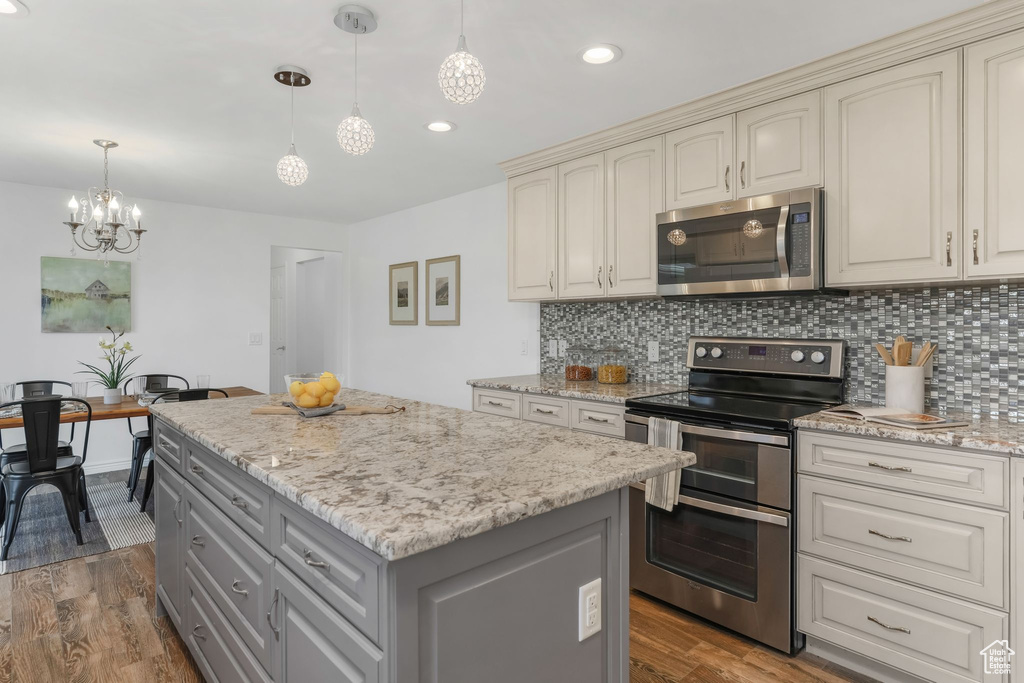 Kitchen featuring gray cabinetry, appliances with stainless steel finishes, cream cabinets, and a notable chandelier
