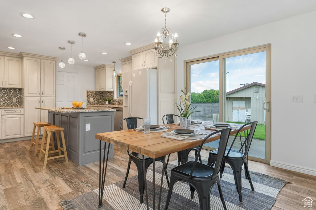 Dining area with recessed lighting, light wood finished floors, baseboards, and a notable chandelier