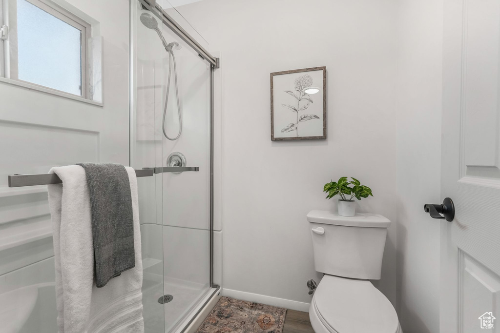 Full bathroom featuring baseboards, a stall shower, and toilet
