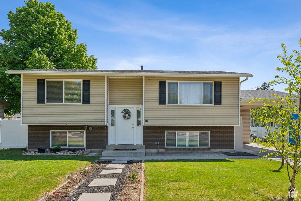 Split foyer home with fence, brick siding, and a front yard
