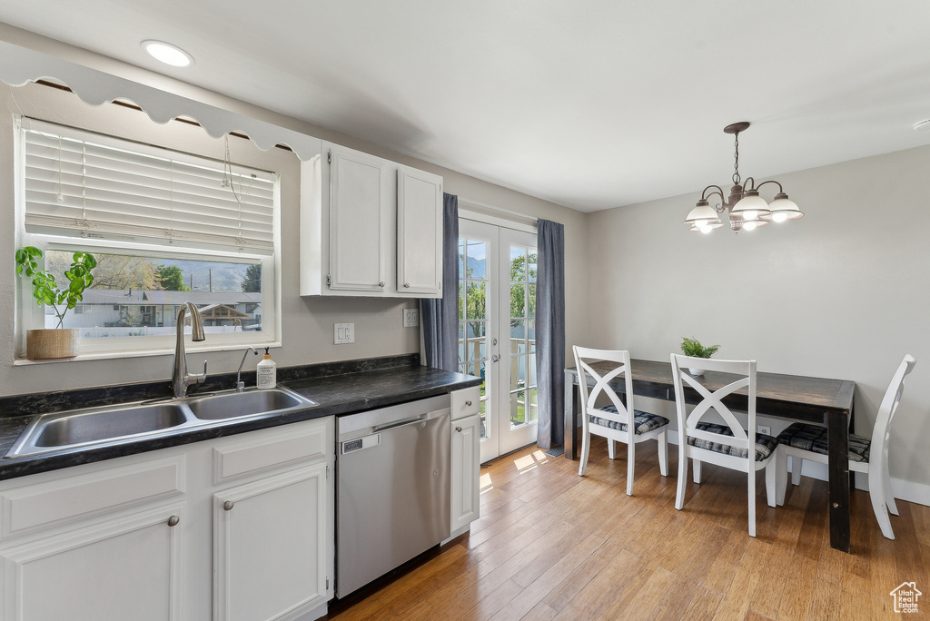 Kitchen featuring a sink, dishwasher, white cabinets, and dark countertops