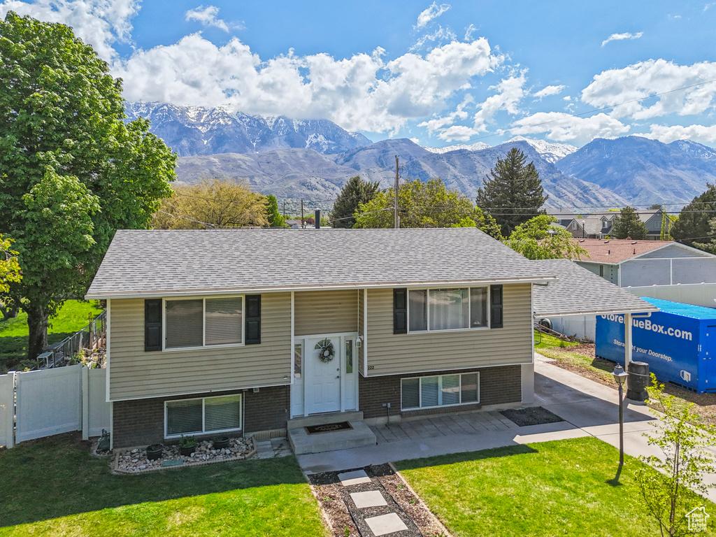 Split foyer home featuring fence, a mountain view, brick siding, and a front yard