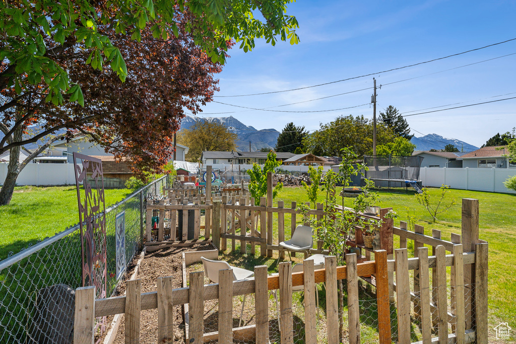 View of yard featuring a fenced backyard, a trampoline, and a mountain view