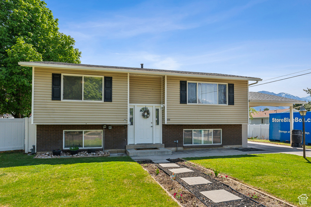 Split foyer home featuring fence, a front yard, and brick siding