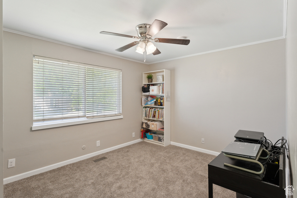 Carpeted home office featuring crown molding, baseboards, ceiling fan, and visible vents