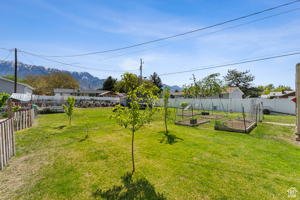 View of yard featuring a mountain view, a garden, and a fenced backyard