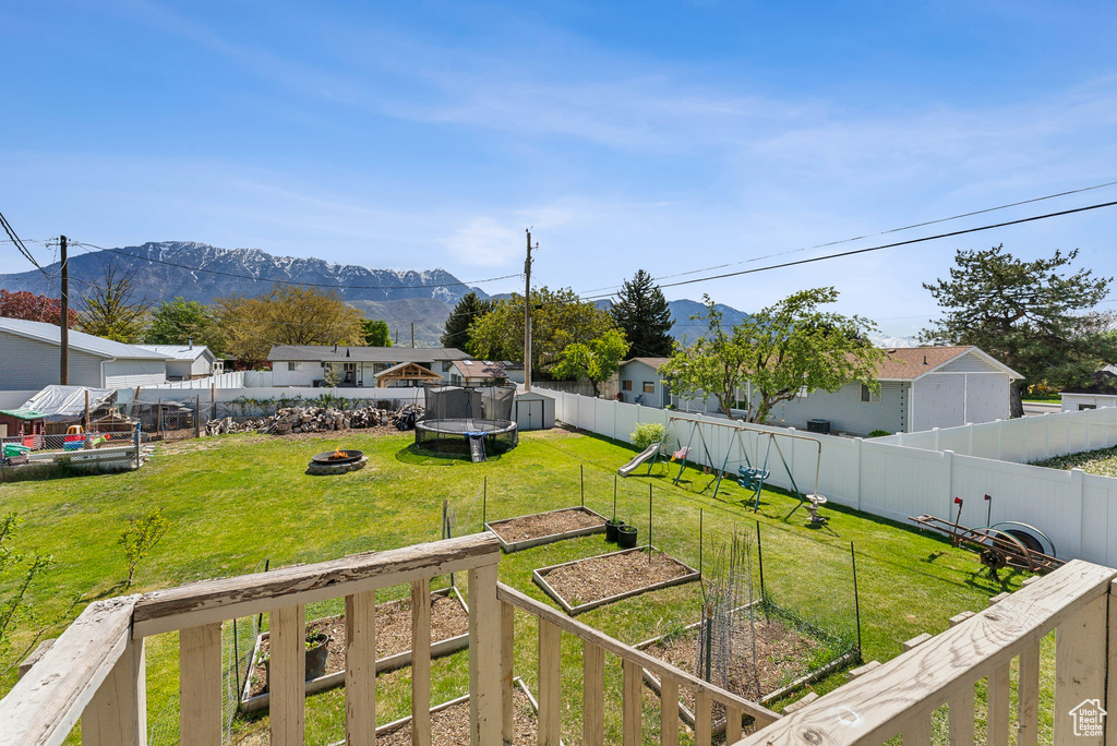 View of yard featuring a fire pit, a mountain view, a fenced backyard, and a vegetable garden