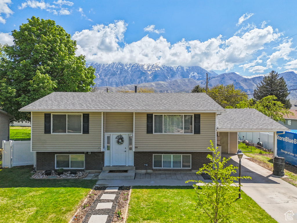 Split foyer home with fence, brick siding, a front yard, a mountain view, and concrete driveway