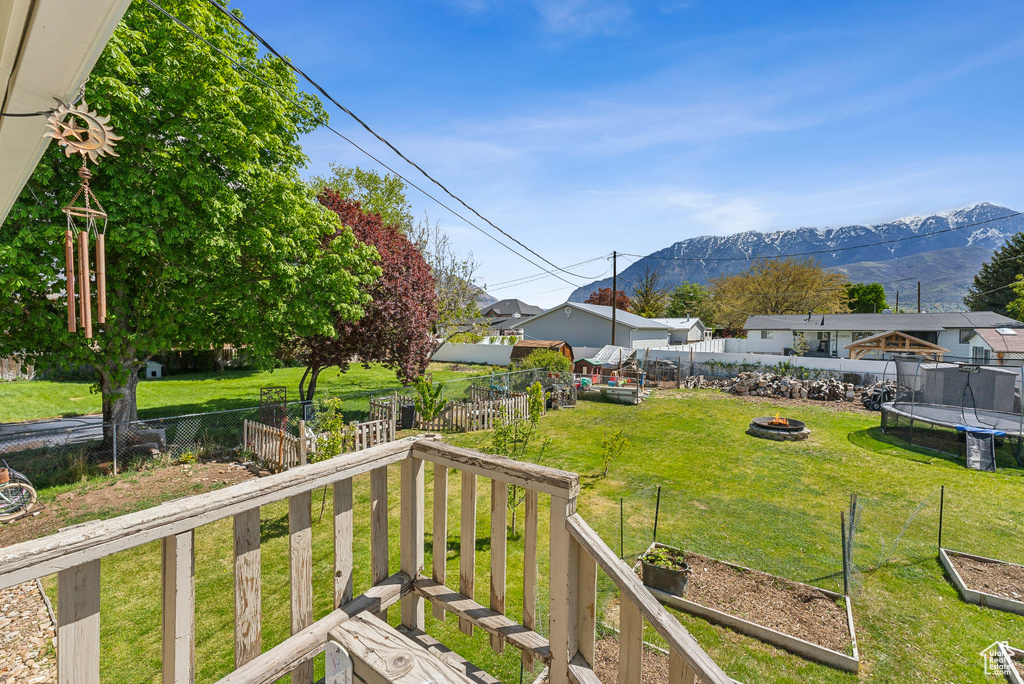 View of yard featuring a fire pit, a fenced backyard, a vegetable garden, a trampoline, and a mountain view