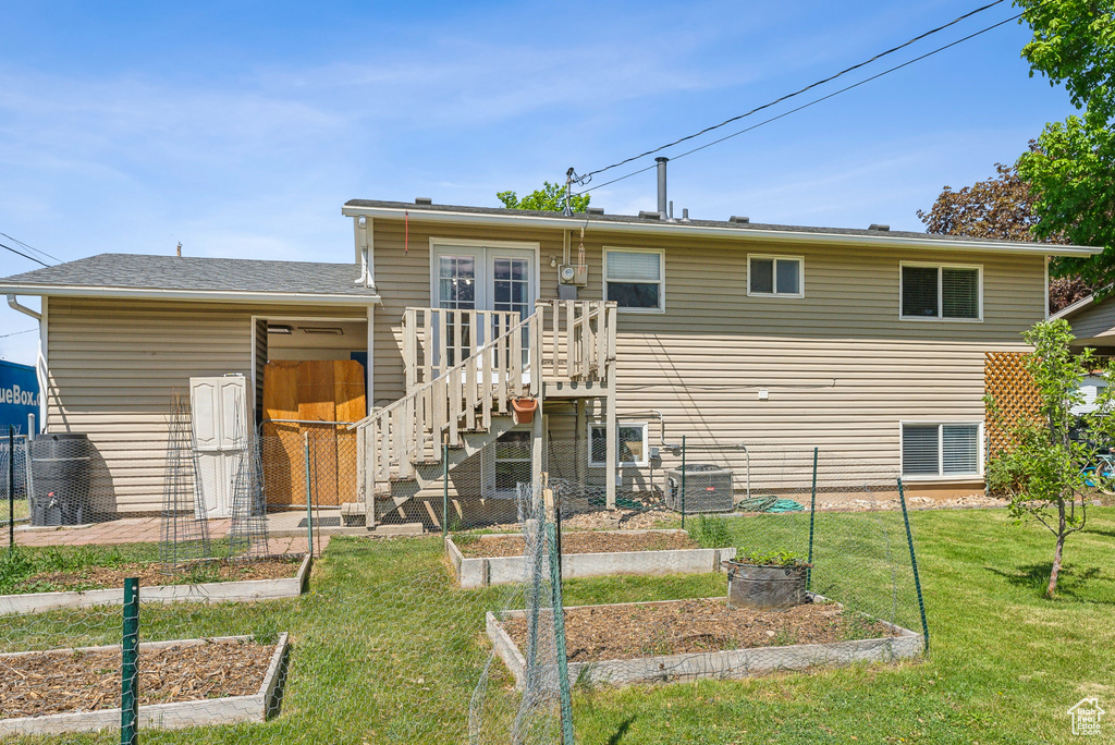 Back of property featuring a lawn, stairway, central AC unit, and a vegetable garden