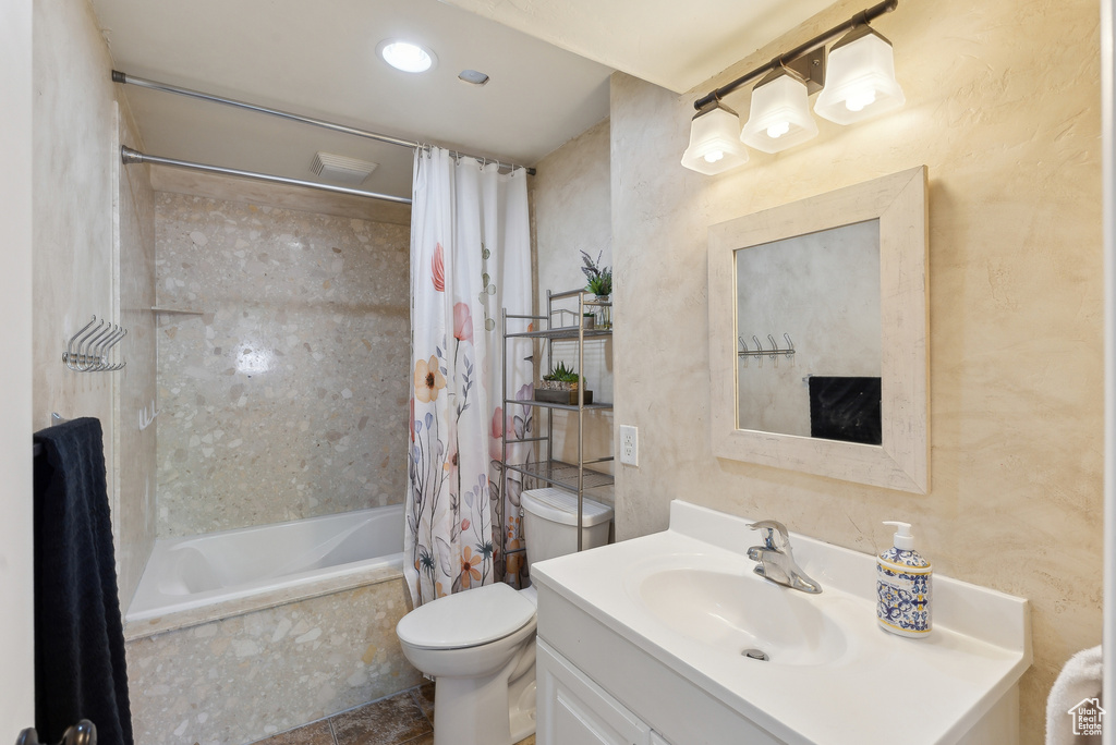 Bathroom with vanity, shower / tub combo, and toilet