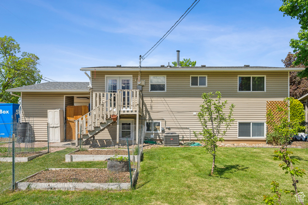 Back of property with a garden, fence, french doors, central air condition unit, and a yard