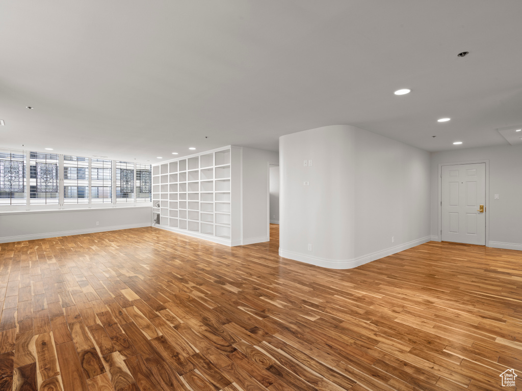 Unfurnished living room featuring recessed lighting, baseboards, built in features, and wood finished floors
