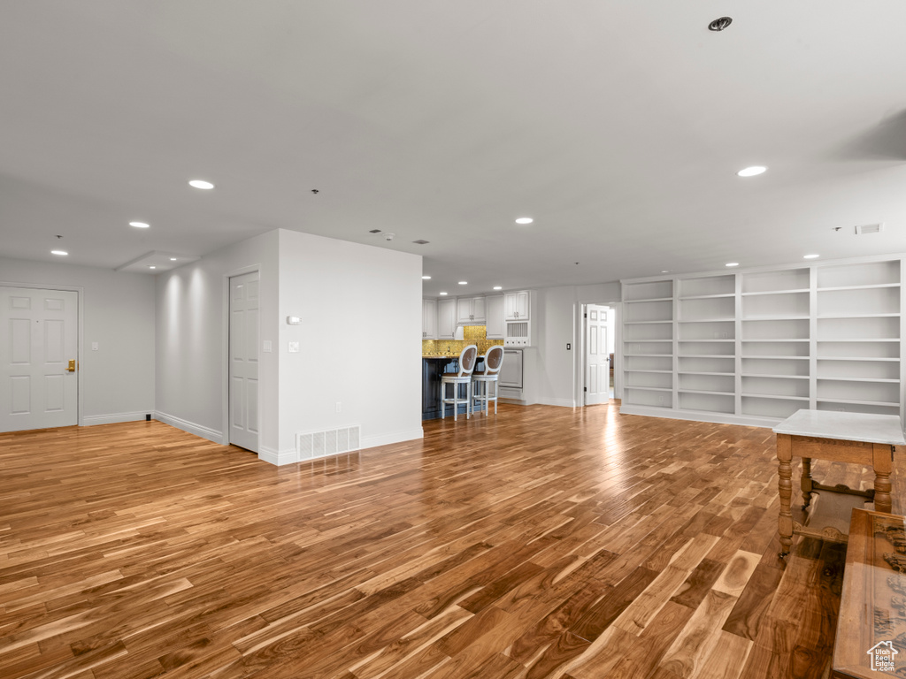 Unfurnished living room with recessed lighting, baseboards, visible vents, and wood finished floors