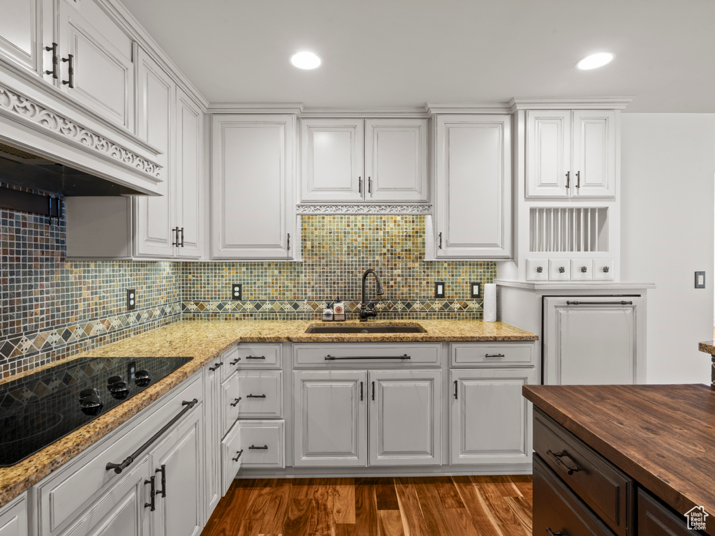 Kitchen with tasteful backsplash, black electric cooktop, a sink, custom range hood, and butcher block countertops
