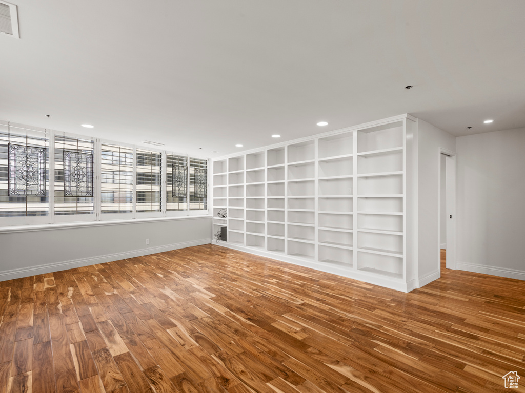 Spare room with built in features, recessed lighting, baseboards, wood finished floors, and visible vents