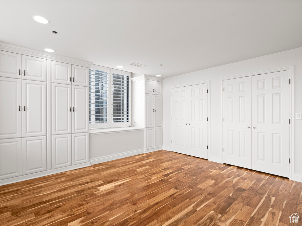Unfurnished bedroom featuring recessed lighting, baseboards, multiple closets, and light wood finished floors