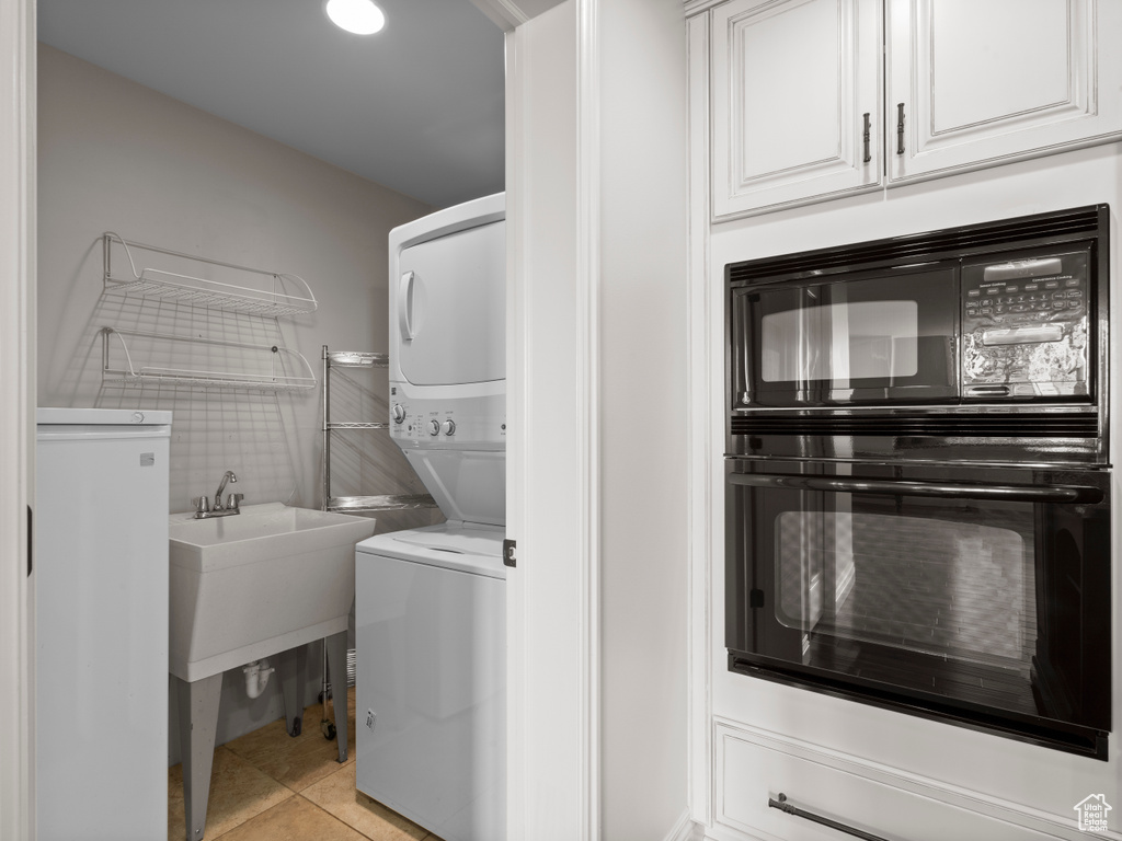 Laundry area with stacked washer / drying machine, light tile patterned floors, and laundry area
