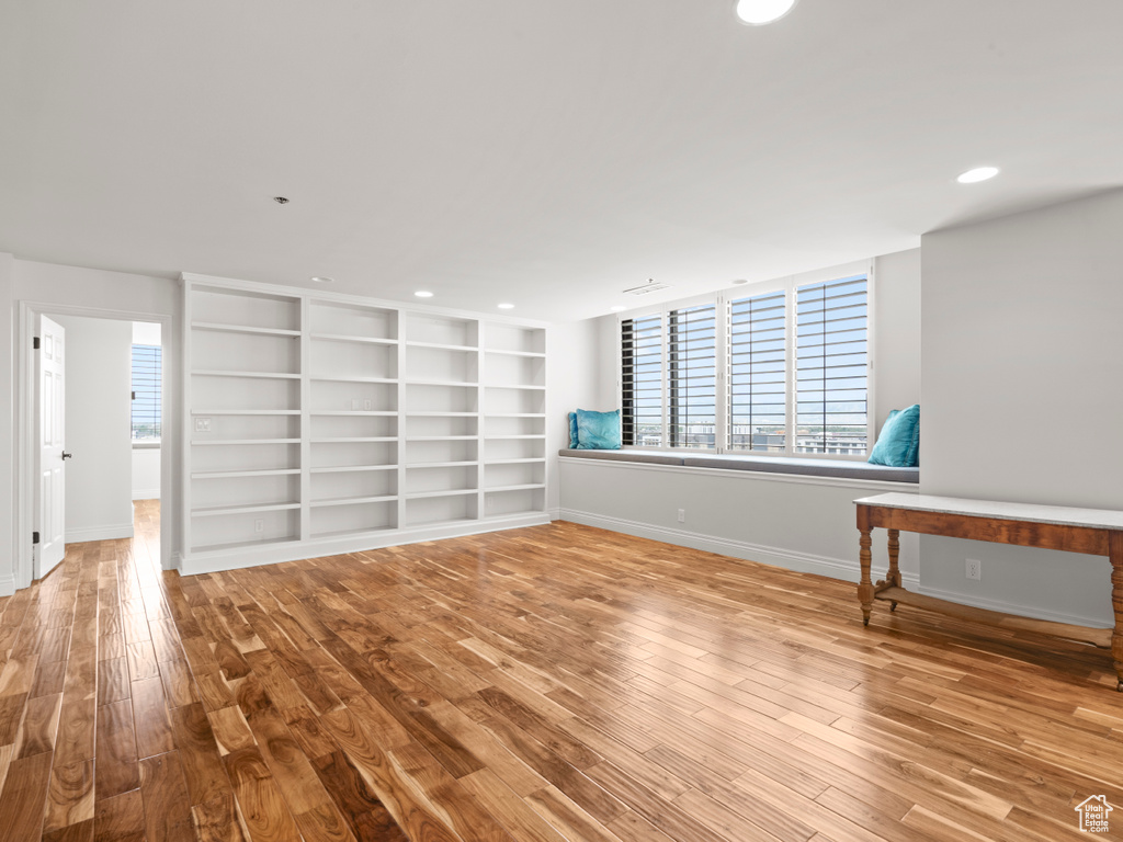 Unfurnished living room featuring baseboards, recessed lighting, wood finished floors, and built in shelves