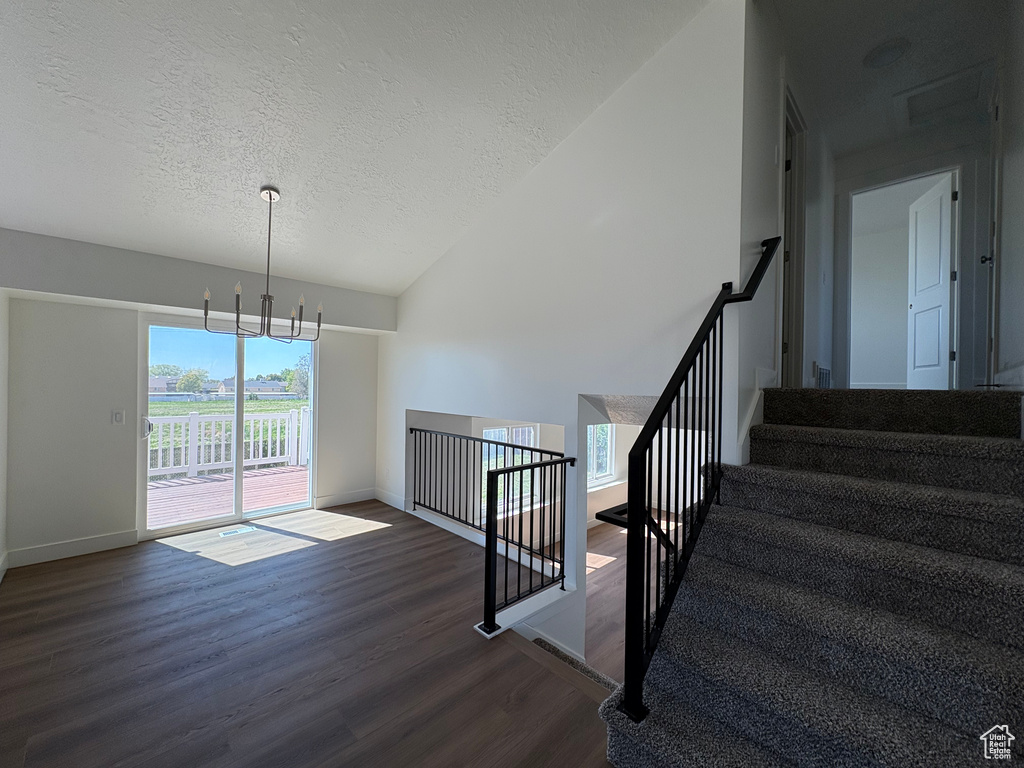 Stairs with wood finished floors, baseboards, a textured ceiling, and a chandelier
