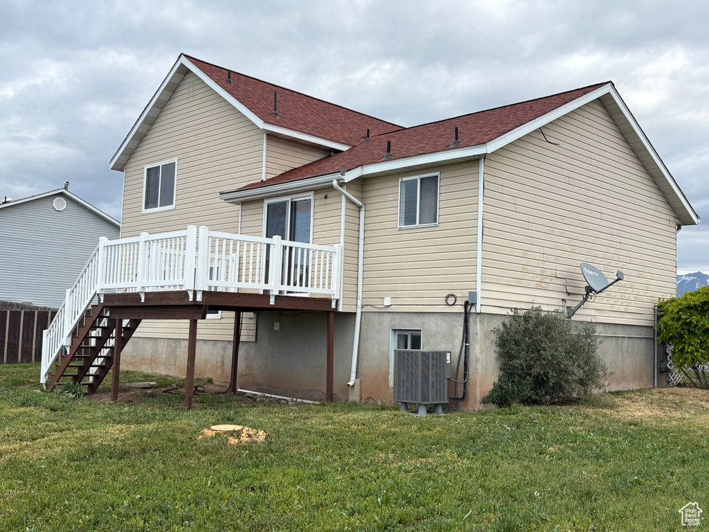 Back of property with a yard, a shingled roof, central AC unit, stairway, and a wooden deck