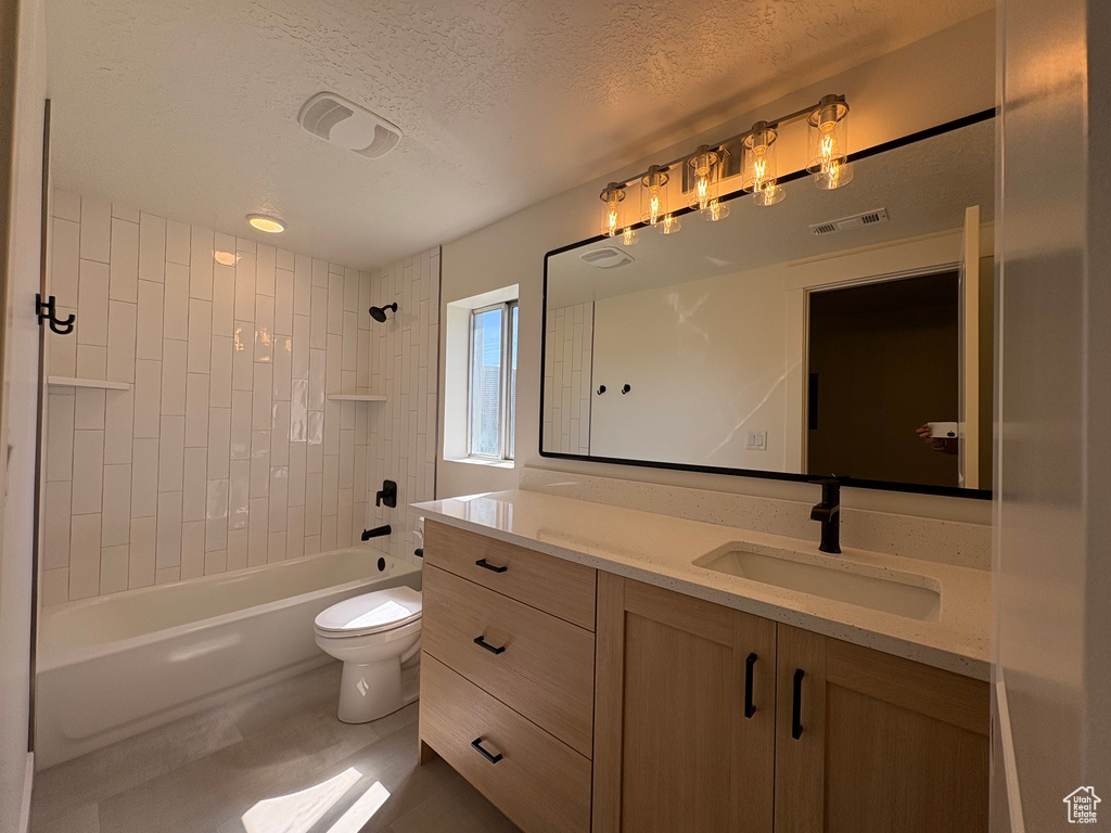 Bathroom with a textured ceiling, visible vents, vanity, toilet, and washtub / shower combination