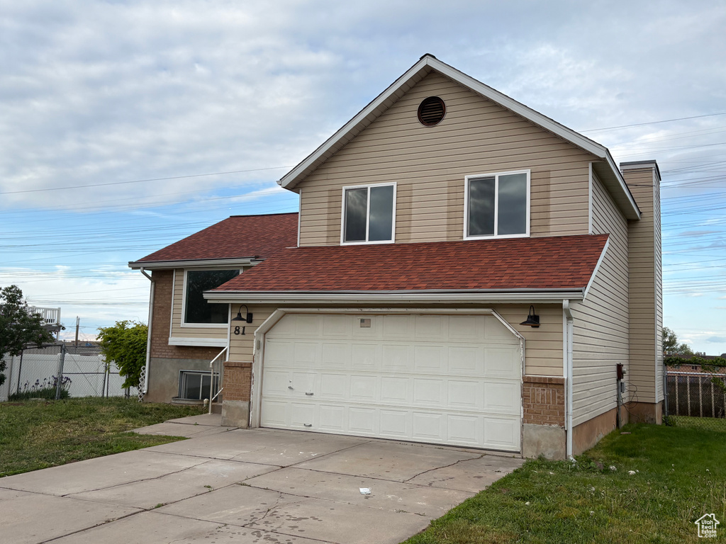 View of front of house with an attached garage, a chimney, fence, a shingled roof, and driveway