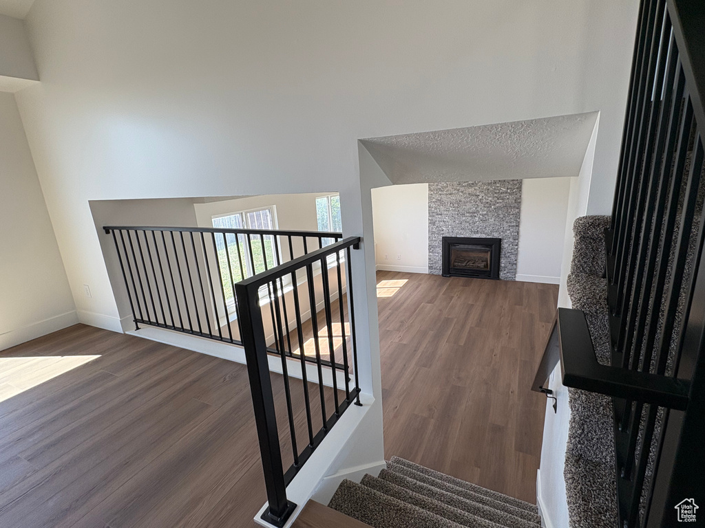 Staircase featuring baseboards, a high ceiling, wood finished floors, and a stone fireplace
