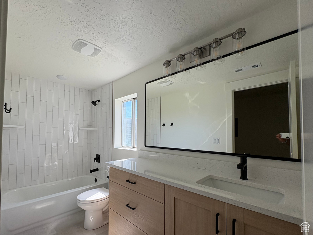 Bathroom featuring vanity, visible vents, toilet, a textured ceiling, and shower / washtub combination