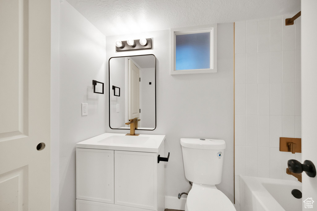 Bathroom with vanity, a textured ceiling, toilet, and shower / washtub combination