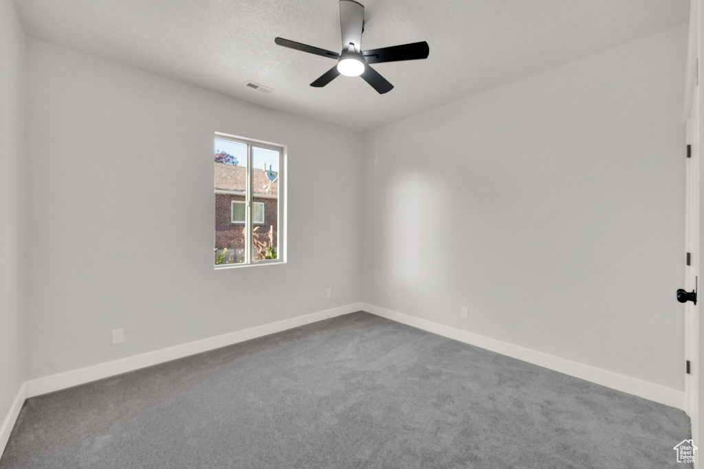 Carpeted empty room featuring a ceiling fan and baseboards