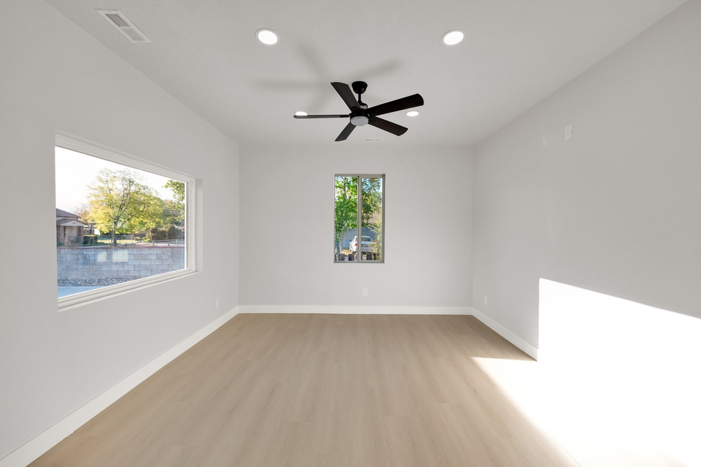 Spare room featuring a ceiling fan, visible vents, light wood-type flooring, baseboards, and recessed lighting