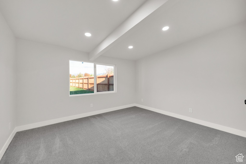 Spare room featuring recessed lighting, baseboards, beam ceiling, and dark carpet