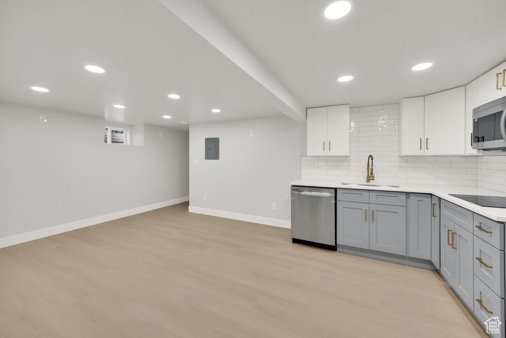 Kitchen featuring backsplash, appliances with stainless steel finishes, a sink, baseboards, and gray cabinetry