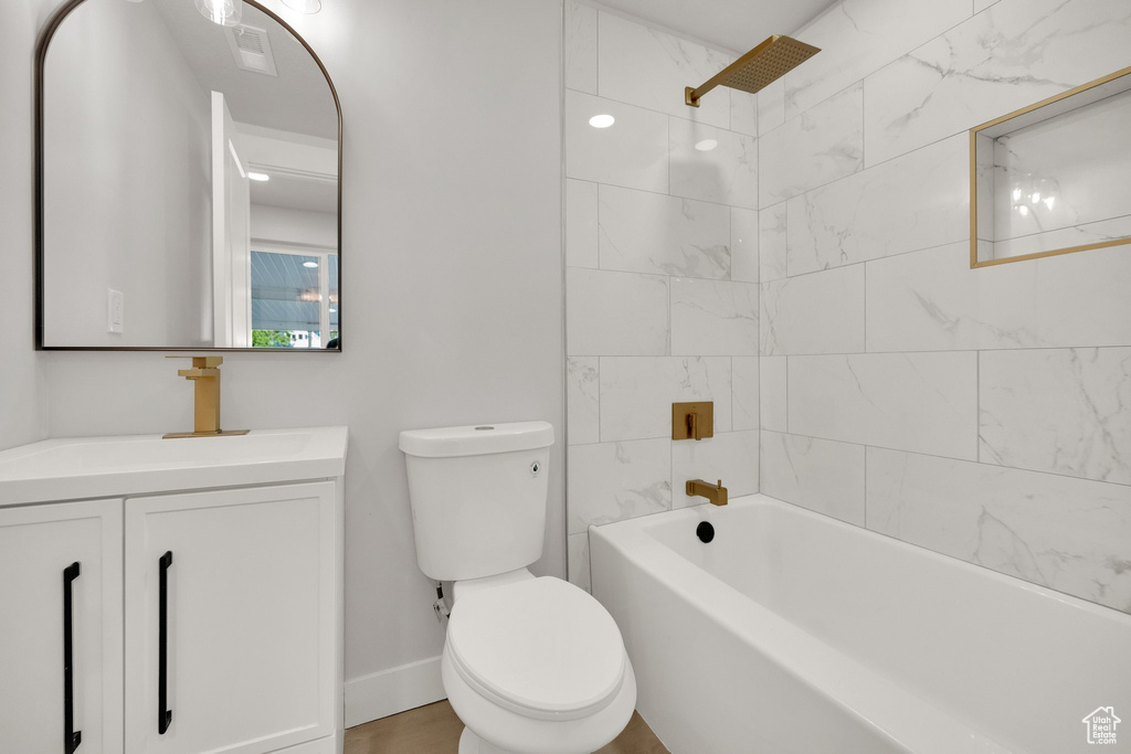 Full bath featuring visible vents, vanity, toilet, baseboards, and shower / tub combination