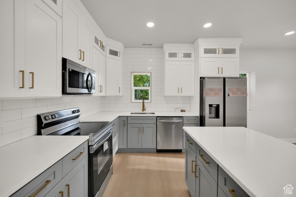 Kitchen featuring stainless steel appliances, gray cabinetry, a sink, and recessed lighting