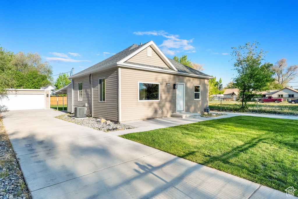Bungalow-style home with an outdoor structure, central air condition unit, a front yard, and fence