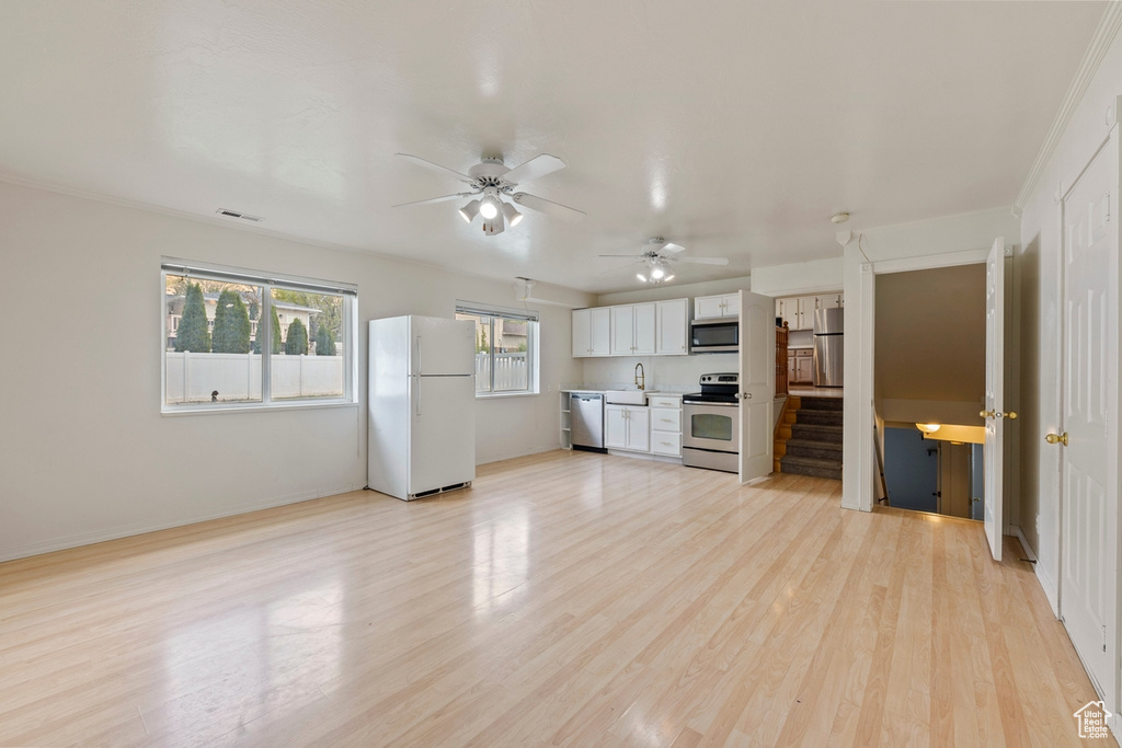 Unfurnished living room with a ceiling fan, visible vents, a sink, stairway, and light wood-style floors