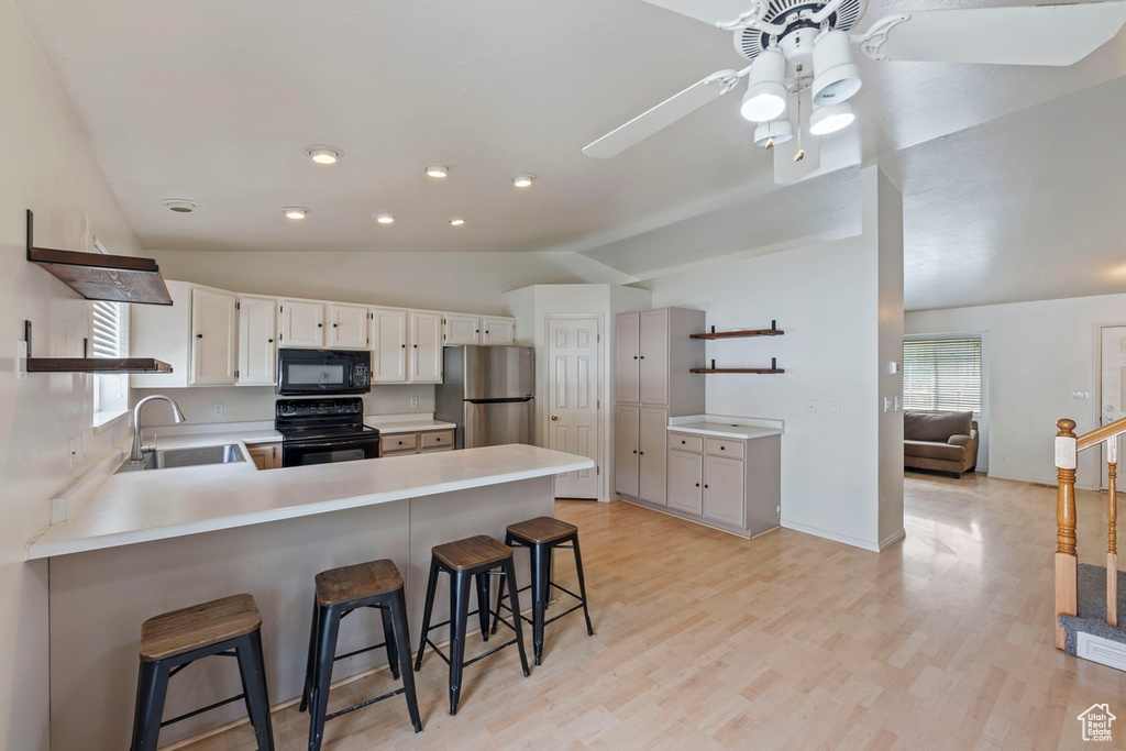Kitchen featuring open shelves, a sink, a peninsula, and black appliances