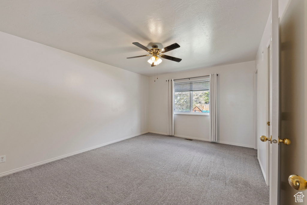 Empty room with baseboards, ceiling fan, and light colored carpet
