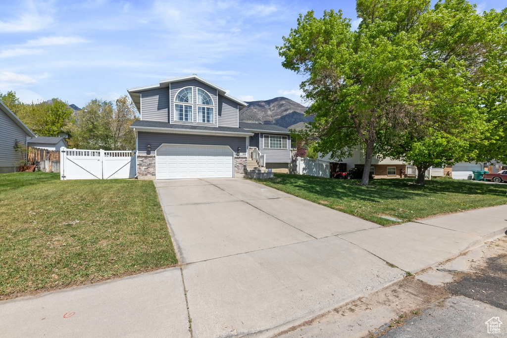 View of front of home featuring fence, an attached garage, a front yard, a gate, and concrete driveway