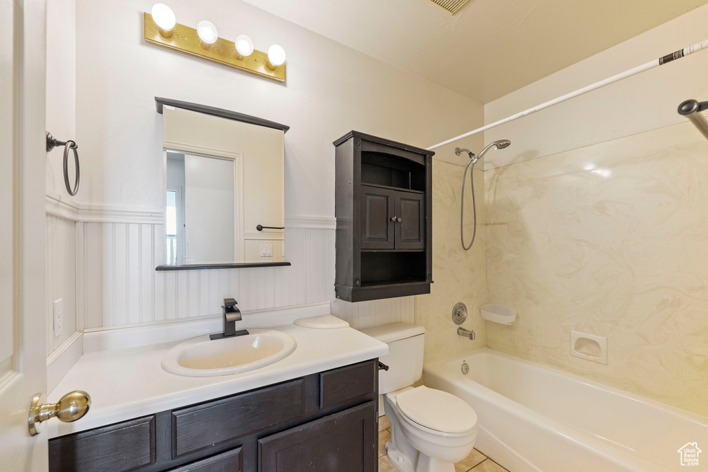 Bathroom with bathtub / shower combination, toilet, wainscoting, and vanity