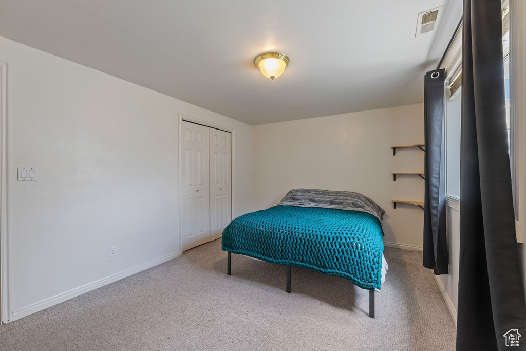 Carpeted bedroom with visible vents, baseboards, and a closet