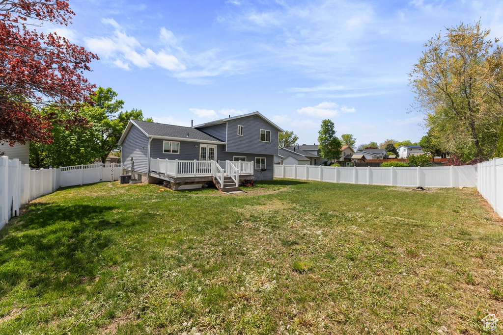 Exterior space with a fenced backyard, a wooden deck, and a lawn